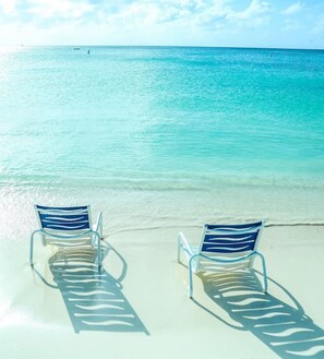 Two sun loungers on a sandy beach with clear turquoise water. - Palm Beach Strip - 2B 2,5B Luxury Condo (Noord)