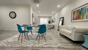 Un salon moderne comprenant un coin repas, un canapé et une horloge murale.