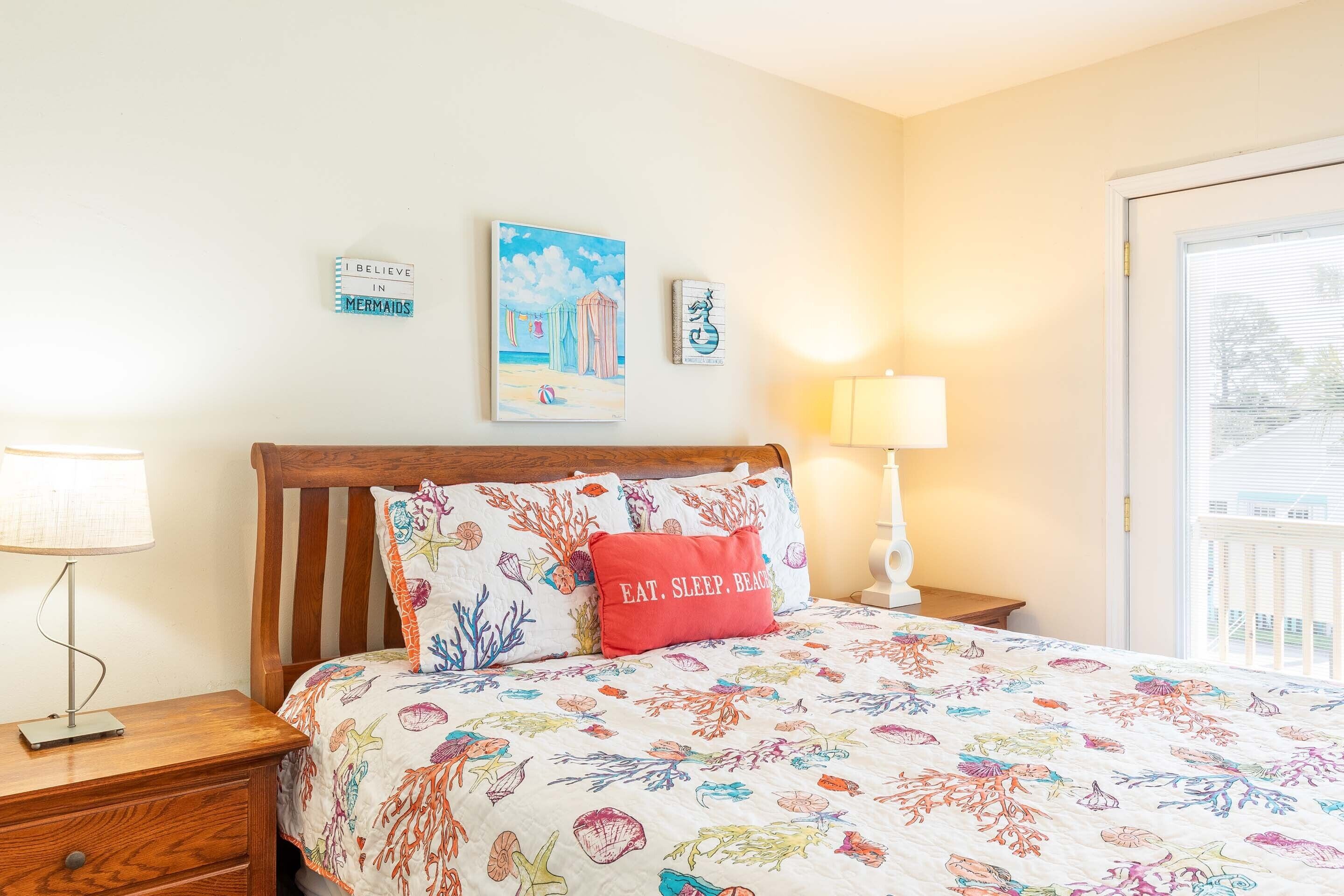 A bedroom with a bed, a nightstand, a lamp, and wall art.