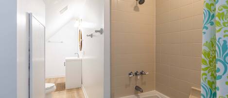A bathroom with a shower, toilet, and sink.