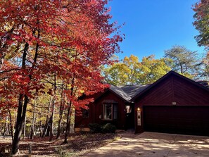 A red cabin with a garage, surrounded by trees with autumn foliage. - In home Games, Gym, & Movie Room+FREE Pool Access! (McGaheysville)