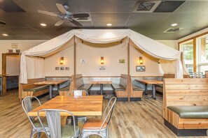 A restaurant with wooden tables and benches, a ceiling fan, and wall-mounted lights. - In home Games, Gym, & Movie Room+FREE Pool Access! (McGaheysville)