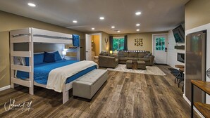 Una habitación compacta con una cama nido, un sofá, una mesita y un refrigerador.