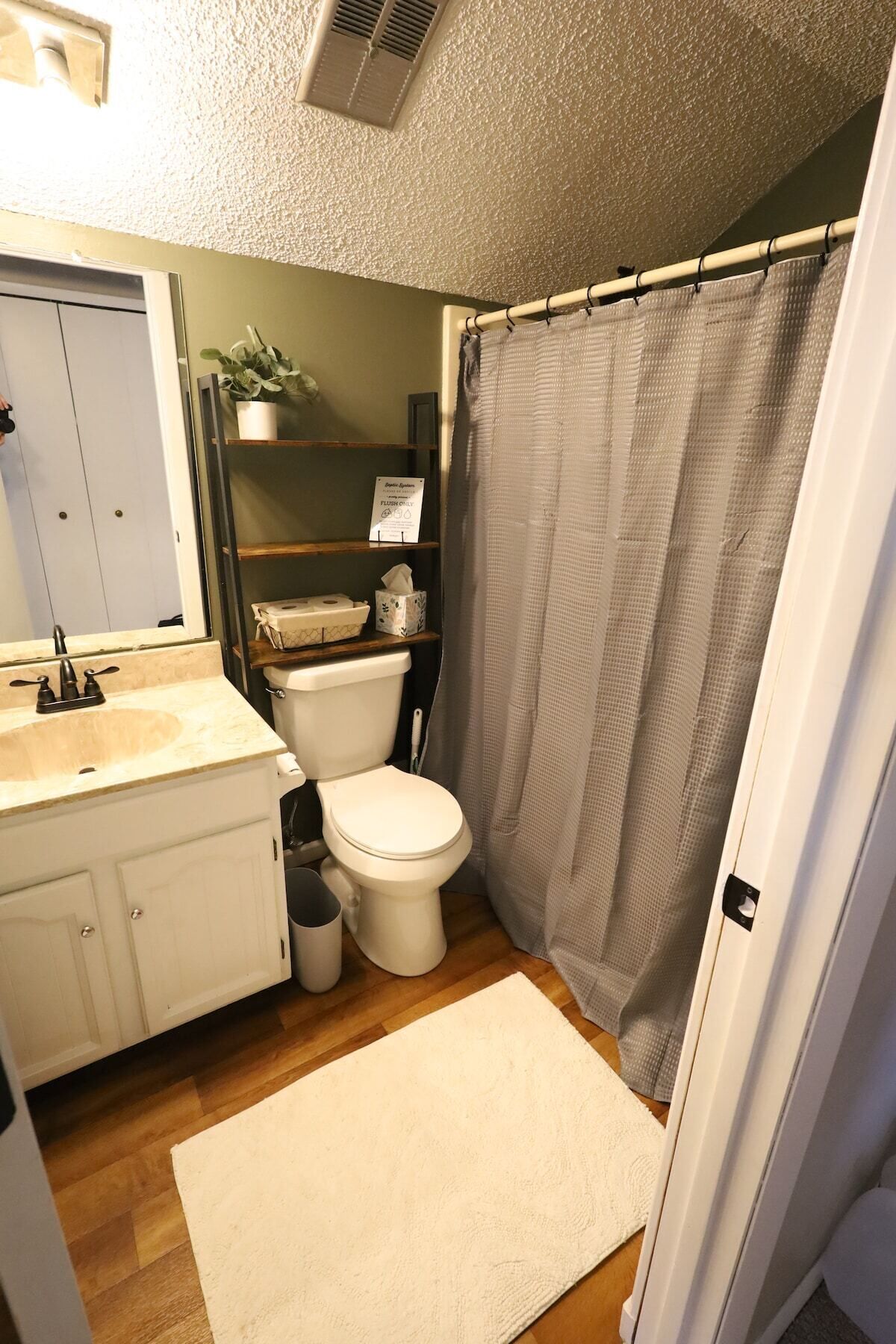 Un bagno piccolo ma funzionale, con WC, lavandino e tenda per la doccia.