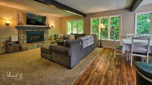 Una sala de estar acogedora con chimenea, un sofá y un televisor instalado en la pared.