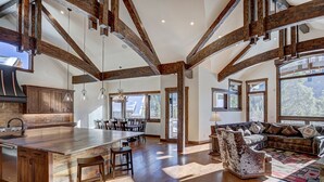 A spacious kitchen with a large island, wooden beams, and a dining area with a sofa and chairs. - Bear Tracks 18 (Keystone)