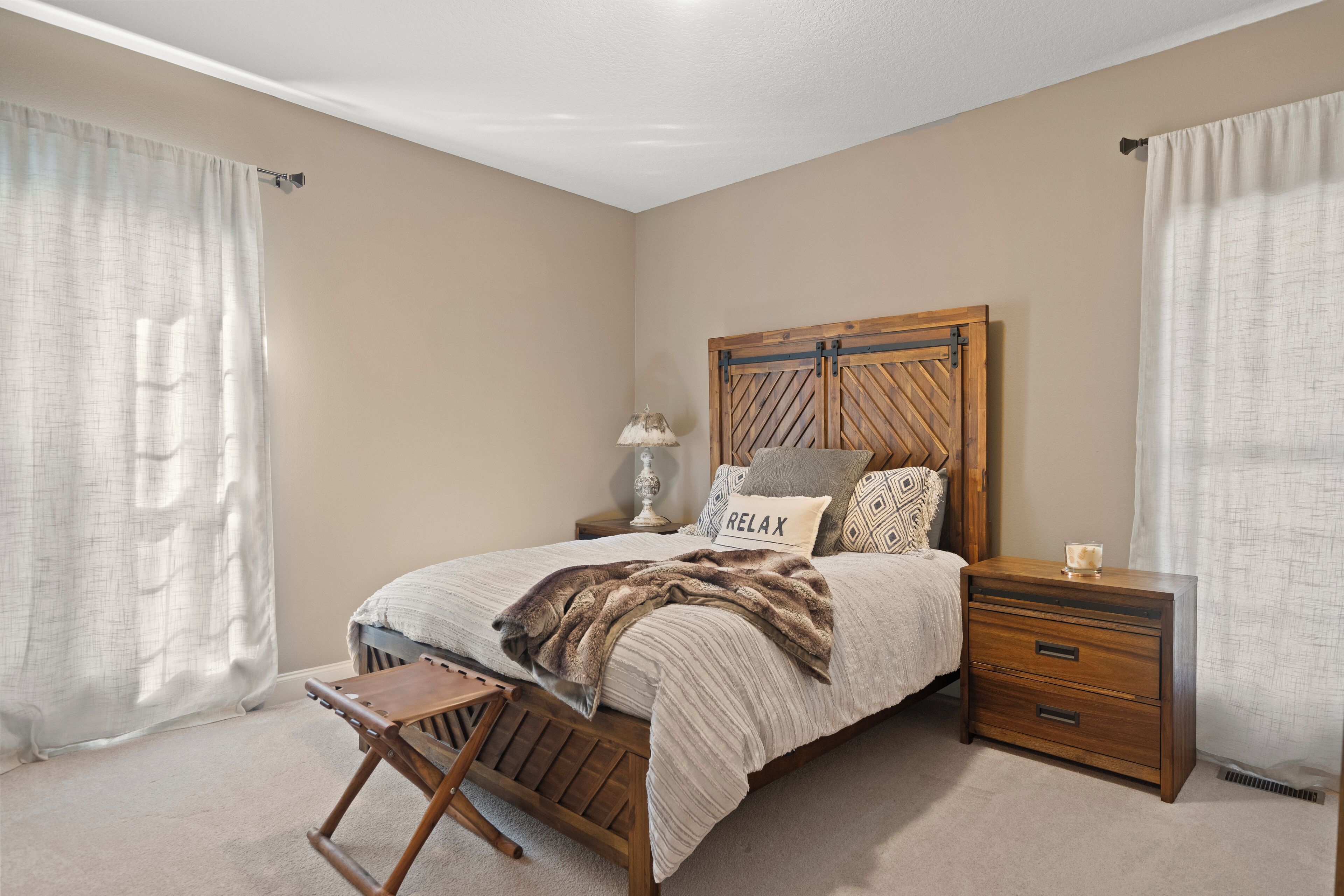 A bedroom with a bed, nightstand, and a small wooden chair.