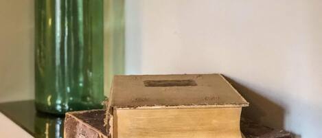 Una botella de vidrio verde y dos libros antiguos sobre una estantería.