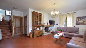 Un salon avec une cheminée, un canapé, une table basse et un escalier menant à une autre pièce.