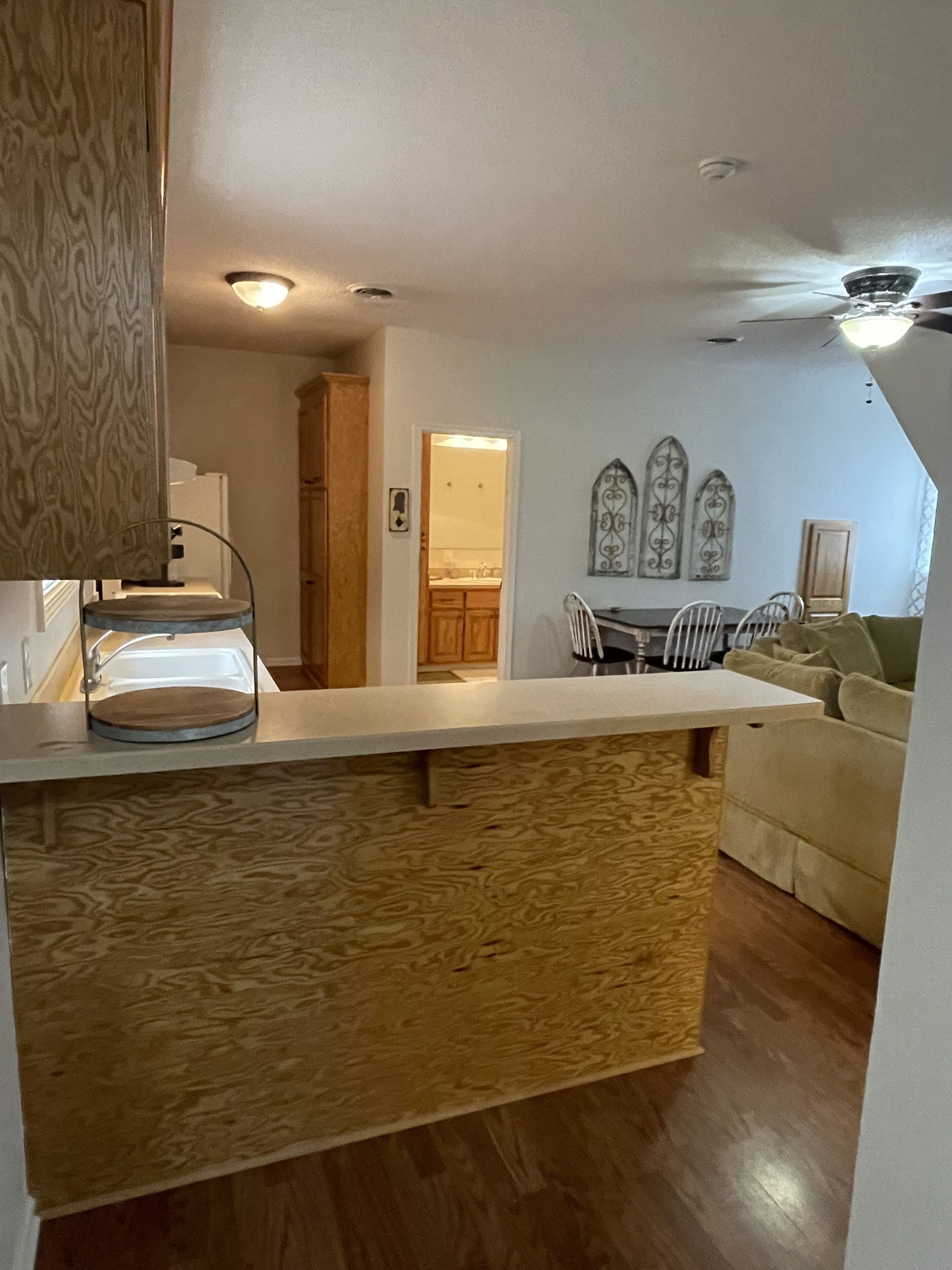A kitchen with wooden cabinets, a central island, and a dining area with a table and chairs.