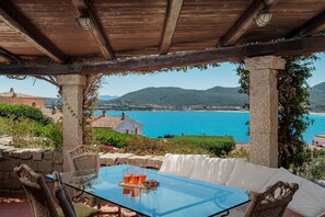 Relax in a serene outdoor space with a stunning coastal view, featuring a glass-top table and wicker chairs.
