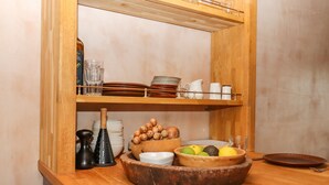 Una cucina con mensole in legno che contengono piatti, ciotole e una composizione di frutta.