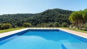 Una piscina rectangular con agua cristalina azul, rodeada por una solana con baldosas.