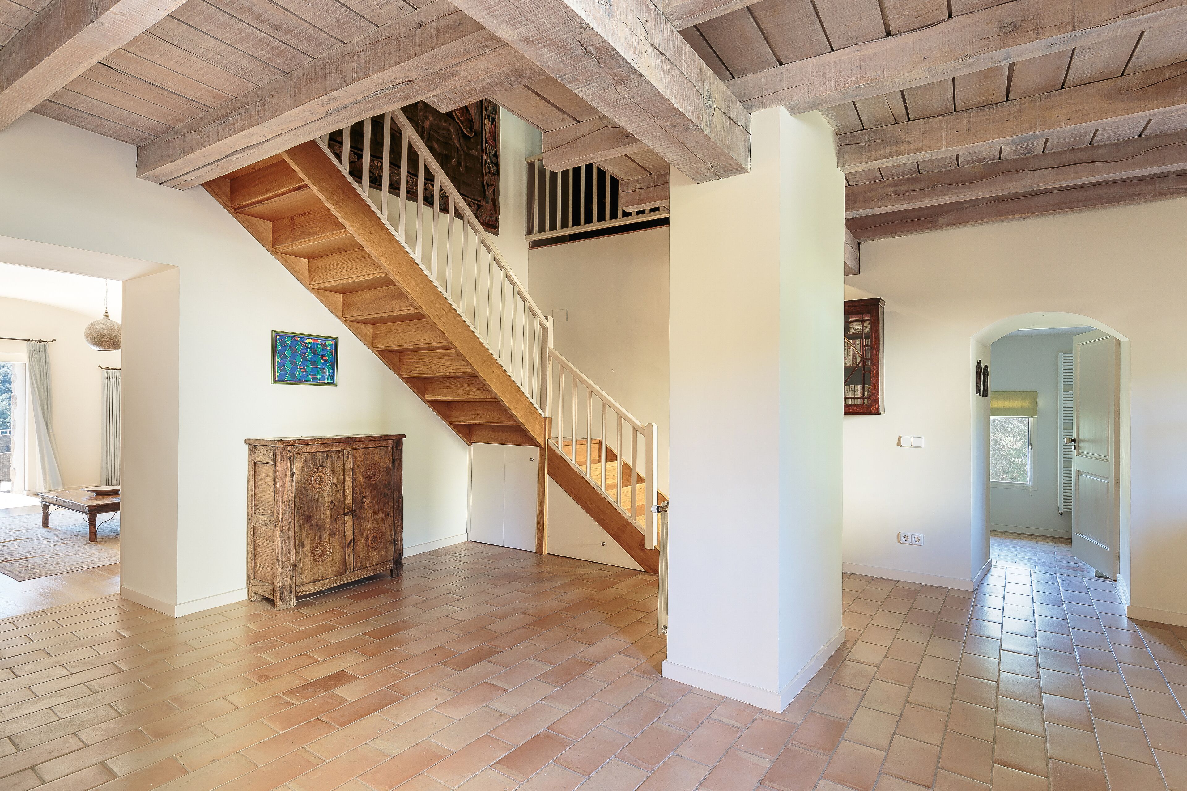 Ein geräumiges Zimmer mit einer Holztreppe, einem großen Schrank und einem Fliesenboden.