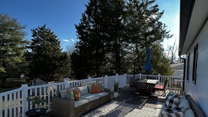 A covered outdoor deck with wicker furniture, a patterned rug, and a white fence. - Alexandria VA spacious, family-friendly 5BR Home near DC (Alexandria)