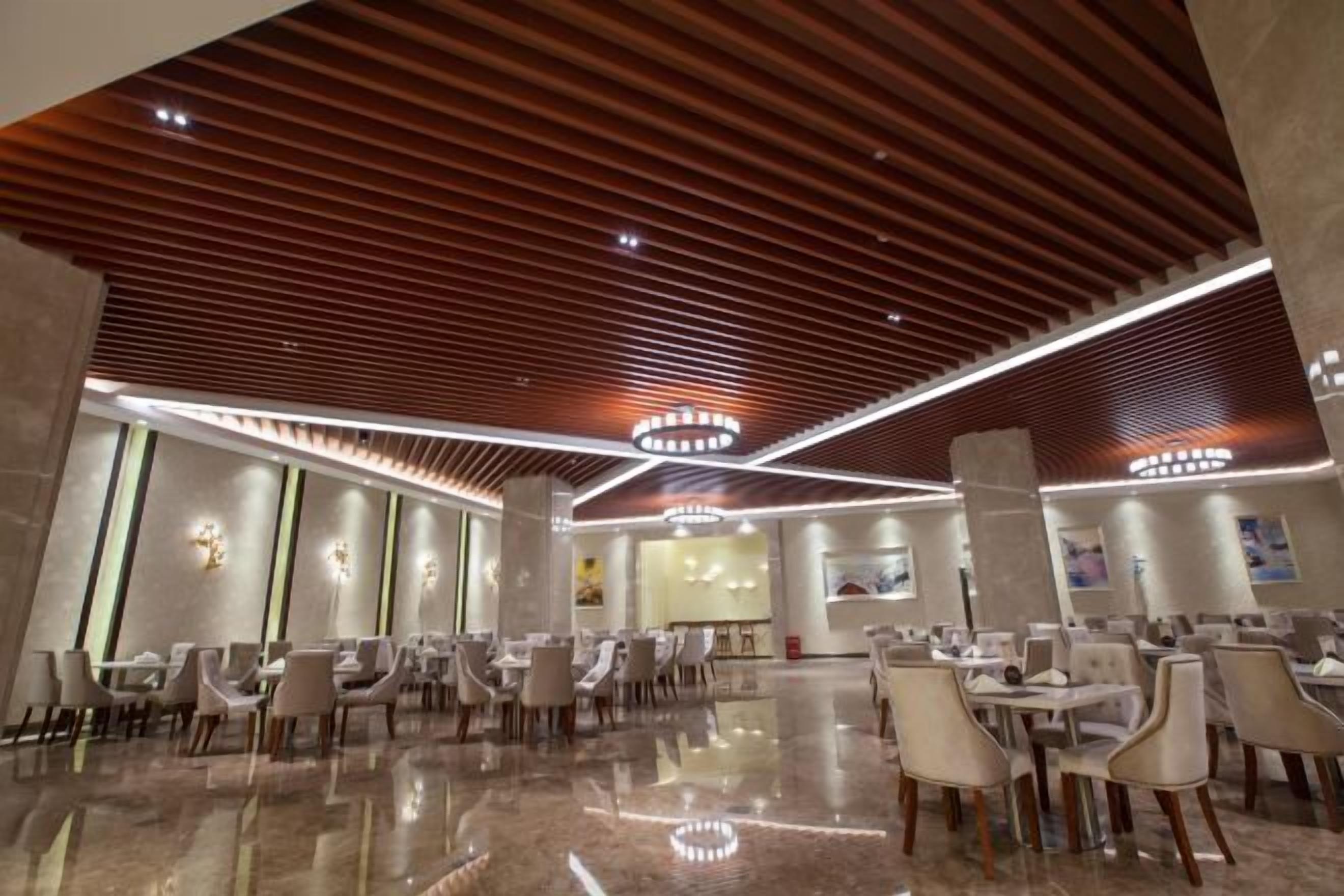Un restaurant spacieux et moderne, doté d’un sol en marbre poli et de lambris en bois au plafond.