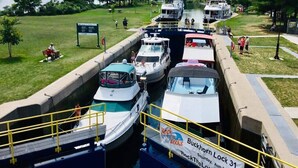 A canal with boats docked, a Canadian flag, and a sign for 'Buckhorn Lock 31' with dates 'Saturday, Aug 25' and 'Saturday, Aug 29'. - Serene, Spacious Waterfront Cottage in Kawartha Lakes w. Hot Tub. Pet-Friendly! (Trent Lakes)