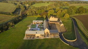A large estate with multiple buildings, expansive green fields, and a winding road. - Beautifully presented Cotswold holiday cottage with a hot tub - Walnut Barn (Great Tew)