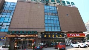 A hotel with a prominent green sign, multiple ground-level shops, and a clear view of the street. - Greentree Inn Jiangsu Changshu Longying Plaza Express Hotel (Suzhou)