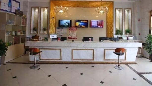 A reception area with a marble counter, two bar stools, a chandelier, and two televisions mounted on the wall. - Greentree Inn Jiangsu Changshu Longying Plaza Express Hotel (Suzhou)
