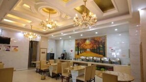 A restaurant with marble-topped tables, wooden chairs, chandeliers, and a large painting on the wall. - Greentree Inn Jiangsu Changshu Longying Plaza Express Hotel (Suzhou)