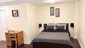 Ein Schlafzimmer mit einem Bett, einem Schreibtisch und zwei an der Wand befestigten Bilderrahmen.