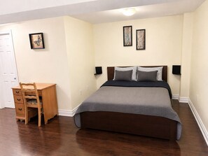 Une chambre à coucher comprenant un lit, un bureau et deux cadres photos fixés au mur.