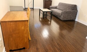 A room with a wooden dining table, a sofa, and a small table.