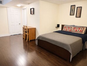 Quarto com cama, escrivaninha e duas imagens emolduradas na parede.