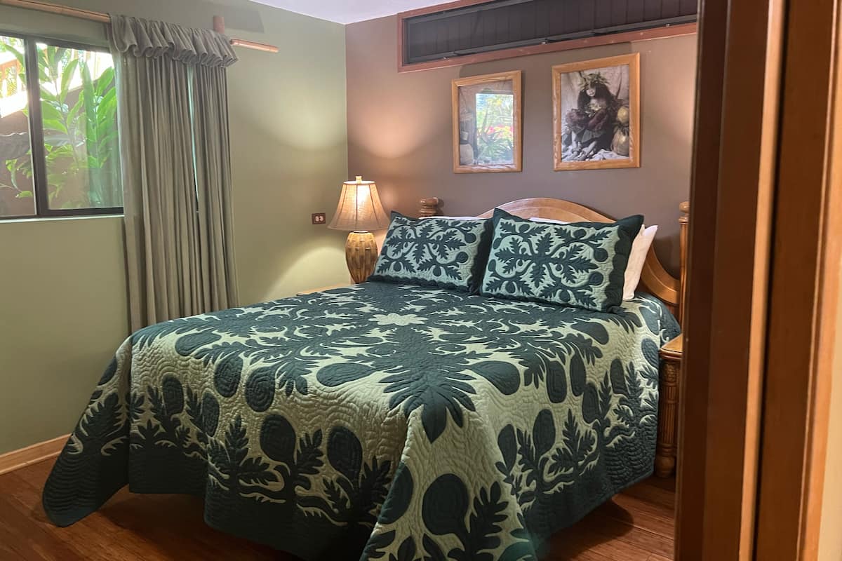 A bedroom with a bed, a nightstand, a lamp, and two framed pictures on the wall.