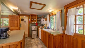 Une cuisine avec des meubles de rangement en bois, un réfrigérateur, une cuisinière, un évier et une machine à café.