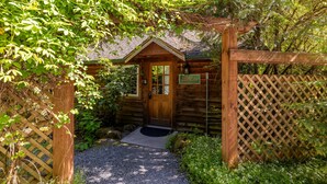Une cabane en bois avec une porte, une enseigne et un chemin de gravier menant à l’entrée.