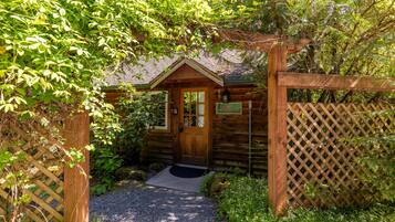 A wooden cabin with a door, a sign, and a gravel path leading to it.