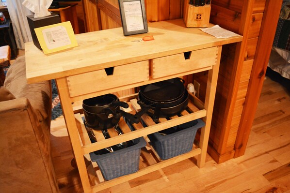 A wooden kitchen cart with two black pots and two blue baskets underneath.