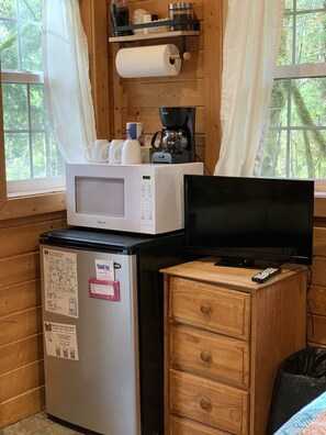 Enjoy a cozy cabin stay with a compact kitchenette featuring a microwave, refrigerator, TV, and coffee maker.