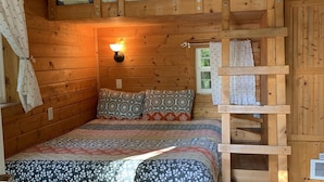 Una habitación acogedora de estilo cabaña con una cama nido, una cama inferior y una escalera.