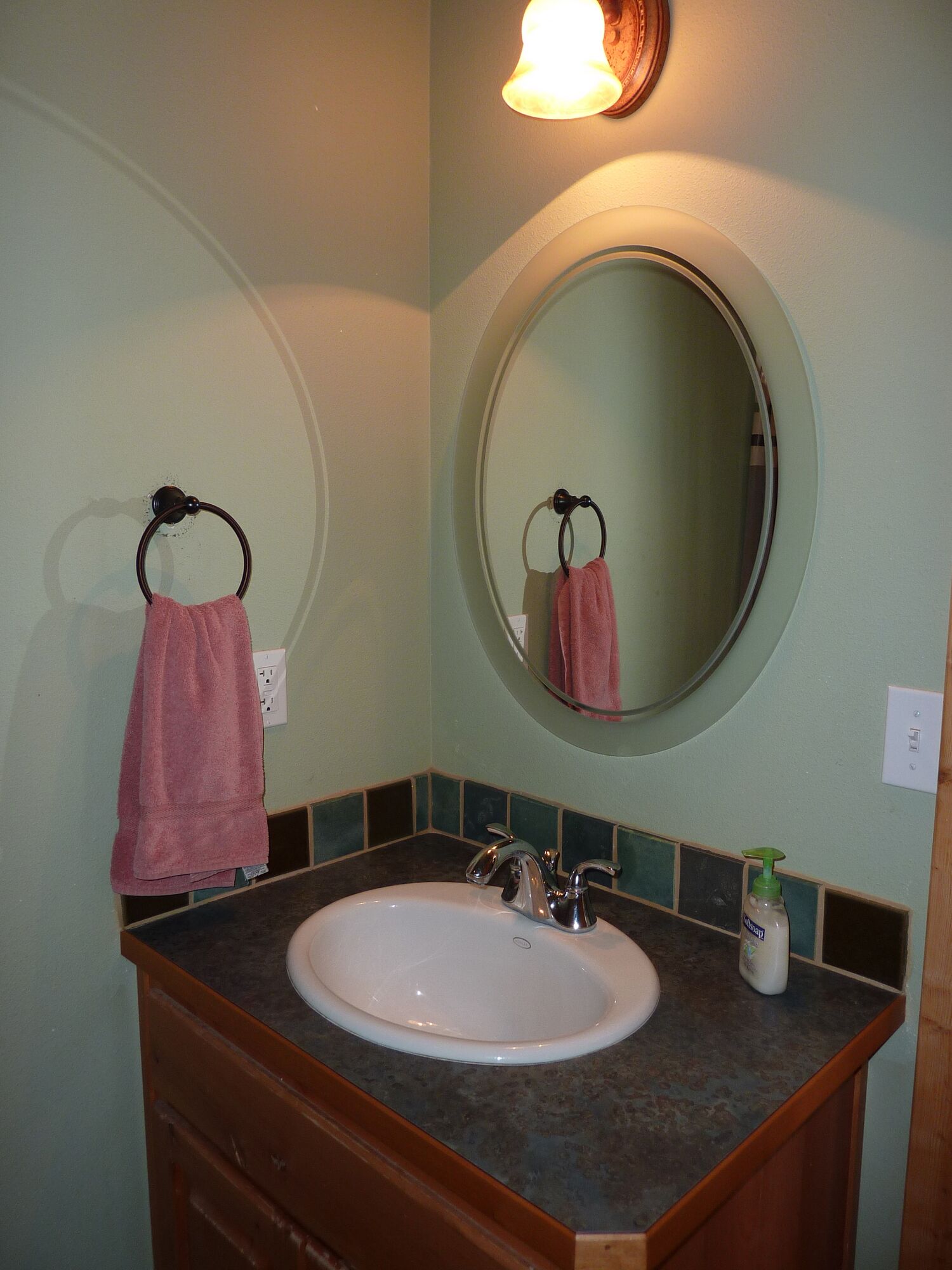 A bathroom with a sink, mirror, and towel rack.