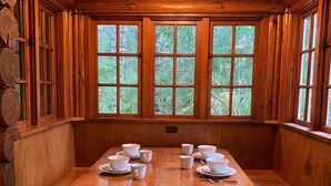 A wooden cabin interior with a large dining table set for four, surrounded by benches.