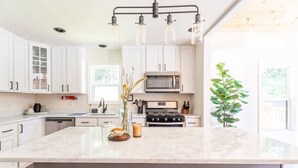 Una cocina moderna con armarios blancos, una isla grande, una estufa y un microondas.