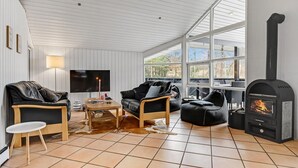 A cozy living room with a fireplace, leather sofas, a TV, and a large window. - Stunning home in Ebeltoft with kitchen (Ebeltoft)