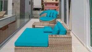 A modern outdoor seating area with wicker furniture and a blue cushion, overlooking a cityscape. - Mantaray Villa #6 Sum (roatan)