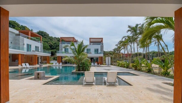 A modern resort with a central pool, lounge chairs, and a tropical garden. - Mantaray Villa #6 Sum (roatan)
