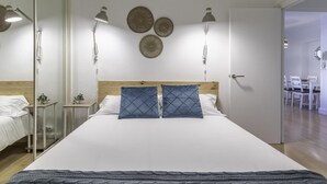 A modern bedroom with a large bed, bedside lamps, and decorative wall plates.