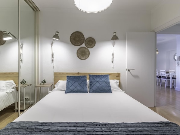 A modern bedroom with a large bed, bedside lamps, and decorative wall plates.