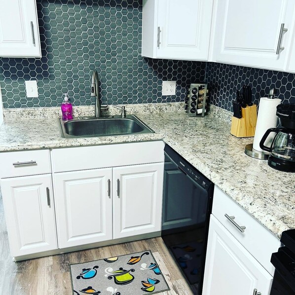 A kitchen with white cabinets, a granite countertop, a stainless steel sink, a coffee maker, and a toaster. - Completely remodeled efficiency unit one block from the Smithville square (Smithville)