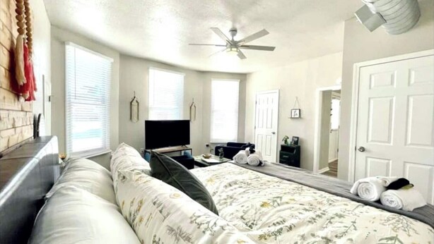 A bedroom with a bed, a TV, a ceiling fan, and a large window. - Completely remodeled efficiency unit one block from the Smithville square (Smithville)