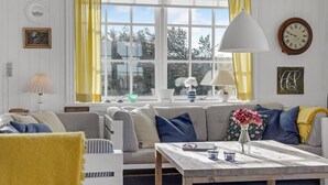 A cozy living room with a sofa, a table with candles, and a window with curtains.