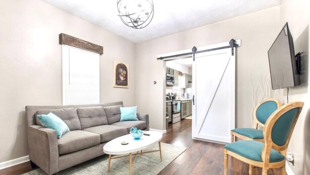 A living room with a grey sofa, a white coffee table, and teal chairs. A kitchen is visible through an open door. - Modern and comfy home five minutes from downtown (Hannibal)