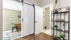 A room with a sliding door leading to a dining area, a metal shelf with decorative items, and a patterned rug. - Modern and comfy home five minutes from downtown (Hannibal)