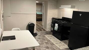 A compact kitchen with a white table, black appliances, and a patterned rug.